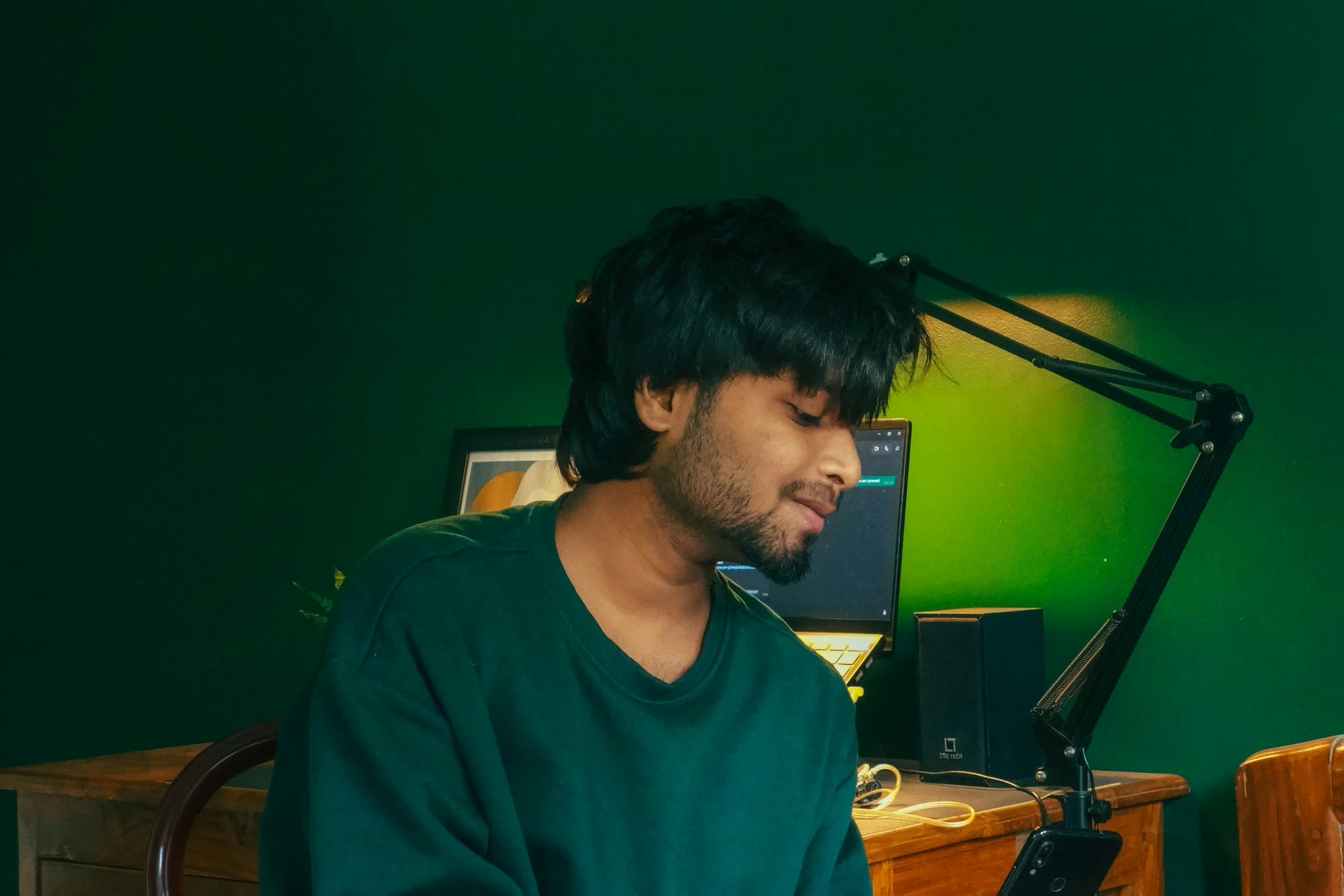 A young professional at a desk in a working studio, the Sierra pin on their sweater.